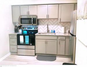 a kitchen with white cabinets and a stove and microwave at Liberty Towne Spring Lake - Premium WiFi Near I-95 & Fort Bragg - Perfect for short or long-term stays in Fayetteville