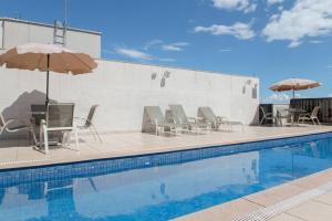 a pool with chairs and umbrellas next to a building at Monumental Nobile- Apart hotel Central in Brasilia