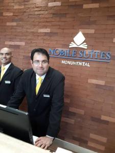 two men in suits standing in front of a laptop at Monumental Nobile- Apart hotel Central in Brasilia