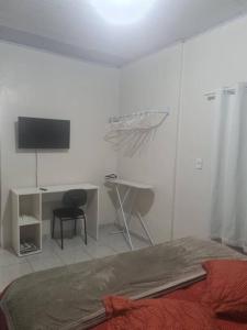um quarto com uma cama e uma secretária com uma televisão em casa de praia em Macapá