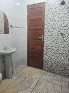 uma casa de banho com um lavatório e uma porta de madeira em casa de praia em Macapá
