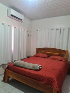 um quarto com uma cama com um edredão vermelho em casa de praia em Macapá