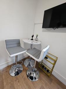 a room with two chairs and a table and a tv at Tiny Studio, 30 min to St. Pancras, North London in London