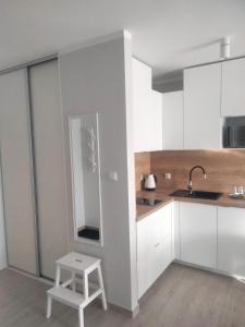 a kitchen with white cabinets and a stool in it at Apartament Nawigator Rybacka 12 b/59 in Kołobrzeg