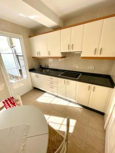 a kitchen with white cabinets and a table and a window at Apartamento Centro Torremolinos con Solarium in Torremolinos