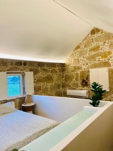 - une chambre avec un lit et un mur en pierre dans l'établissement Quinta Lourenca - Vila do Conde, à Vilar