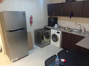 a kitchen with a refrigerator and a washing machine at Calm Partition Room Near Mashreq Metro in Dubai