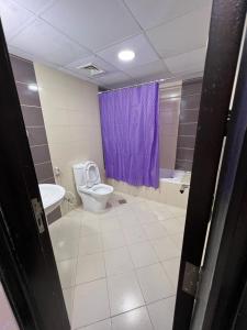 a bathroom with a toilet and a purple shower curtain at Calm Partition Room Near Mashreq Metro in Dubai