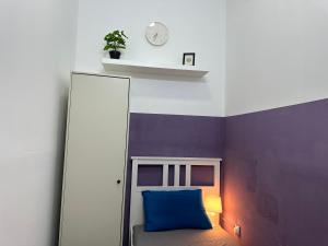 a room with a bed with a blue pillow and a clock at Calm Partition Room Near Mashreq Metro in Dubai