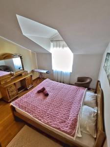 Schlafzimmer mit einem Bett mit einer rosa Bettdecke und einem Spiegel in der Unterkunft Apartmani Kenova 4 in Herceg-Novi