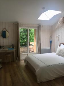 a bedroom with a bed and a desk and a window at Maison l'heure bleue in Lanton