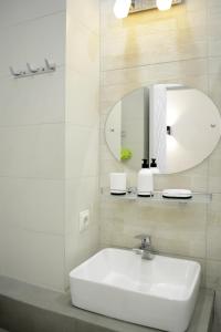 a white bathroom with a sink and a mirror at Paliashvili 90 - VAKE Park 2BR Apartment in Tbilisi City