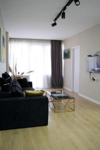 a living room with a black couch and a glass table at Paliashvili 90 - VAKE Park 2BR Apartment in Tbilisi City