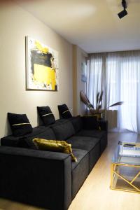 a living room with a black couch and a table at Paliashvili 90 - VAKE Park 2BR Apartment in Tbilisi City