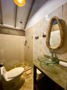 a bathroom with a sink and a toilet and a mirror at Restaurante, Hostal y Spa Mama Neyumun in El Zaino
