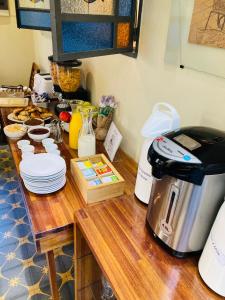 a table with a coffee maker and plates on it at Posada Boutique Le Vrero in Colonia del Sacramento