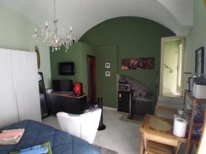 una sala de estar con paredes verdes y una lámpara de araña. en Armony House, en Trecastagni