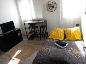 Un dormitorio con una cama con almohadas amarillas y una mesa. en Petit cocon Tarbais -wifi-parking en Tarbes