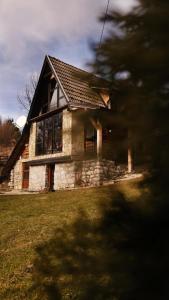 una casa in pietra con tetto su un prato di Planinska Koliba ABA-TARA a Bajina Bašta