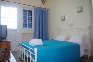 a bedroom with a bed with blue sheets and a television at Rania Studios in Poros