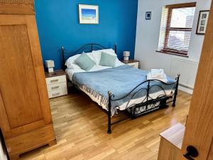 a bedroom with a bed with blue walls and wooden floors at Yr Encil in Gaerwen