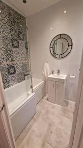 La salle de bains est pourvue d'une baignoire, d'un lavabo et d'un miroir. dans l'établissement Inviting 3-Bed Apartment in Newcastle upon Tyne, à Newcastle upon Tyne