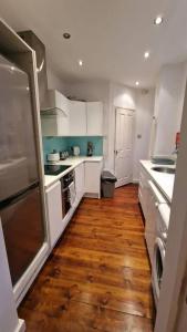a kitchen with white cabinets and a wooden floor at Inviting 3-Bed Apartment in Newcastle upon Tyne in Newcastle upon Tyne