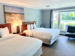 Habitación de hotel con 2 camas y ventana en Elk Rapids Lakeshore Inn, en Elk Rapids