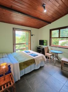 a bedroom with a bed and a desk and a table at Casa Fofa! No Coração de Araras! in Araras Petropolis