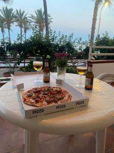 uma pizza sentada numa mesa com dois copos de vinho em Apartamento lujoso en primera linea de playa em Castell de Ferro