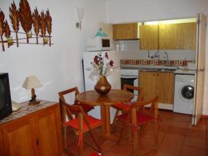 una cocina con una mesa con sillas y un jarrón con flores en Apartamento Ariadna, en Albufeira