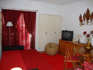 1 dormitorio con cama roja y TV en Apartamento Ariadna, en Albufeira