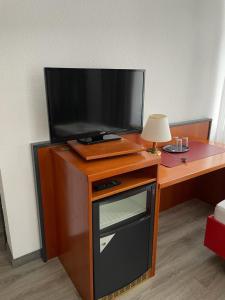 einen TV auf einem Holzständer mit einem Tisch in der Unterkunft Hotel Birkenwerder in Birkenwerder