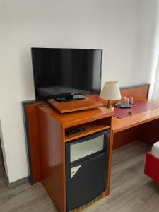 a television on a wooden stand with a table at Hotel Birkenwerder in Birkenwerder