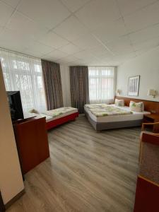 a large room with two beds and a television at Hotel Birkenwerder in Birkenwerder