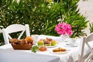 un tavolo bianco ricoperto di piatti di cibo e fiori rosa di PELAGO BUNGALOWS a Skala Potamias