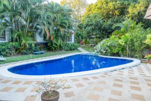 una piscina azul en un patio con árboles en Hotel Aeropuerto, en Alajuela