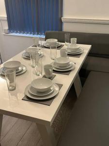 a white table with plates and glasses on it at Home from Home in Manchester