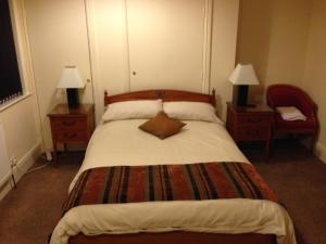 um quarto com uma cama grande, 2 candeeiros e uma cadeira. em Victoria hotel em Holywell