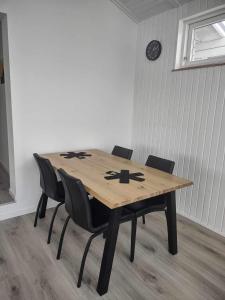 einem Holztisch mit Stühlen und einer Uhr an der Wand in der Unterkunft Ilulissat Hostel in Ilulissat
