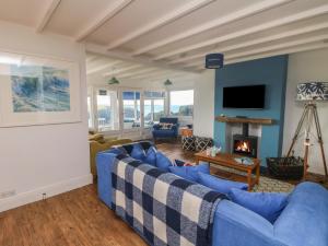 a living room with blue couches and a fireplace at Gwillen in Mawgan Porth