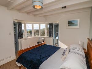 a bedroom with a large bed and windows at Gwillen in Mawgan Porth