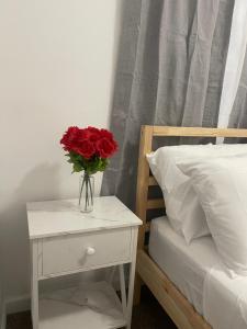 a vase of red roses on a table next to a bed at SUITE JESUS ROOM 3 in Paterson