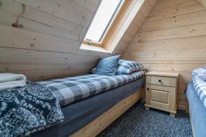 1 cama individual en una cabaña de madera con ventana en Domki na Wiyrchu, en Biały Dunajec