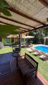 una terraza de madera con un banco y una piscina en Pousada Tropicália, en Arraial d'Ajuda