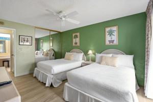 two beds in a room with green walls at Plantation Hale G14 in Kapaa