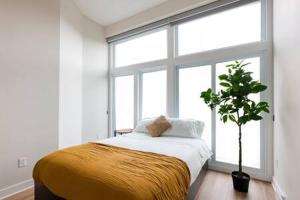 um quarto com uma cama e uma grande janela em Beautiful 2 BDR with Sofa Bed and Sky Light em Montreal