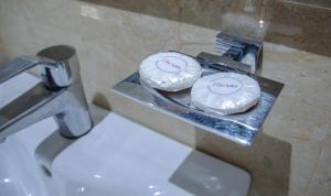 zwei weiße Teller auf einem Tablett neben einem Waschbecken in der Unterkunft Hotel ByHours Las Américas in Bogotá