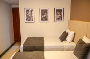 a hotel room with two beds and three pictures on the wall at Hotel ByHours Las Américas in Bogotá