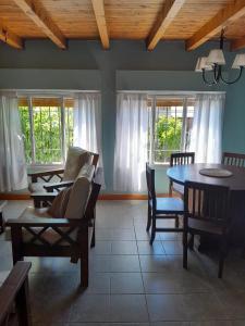 uma sala de estar com uma mesa, cadeiras e janelas em Achalay Houses em San Carlos de Bariloche